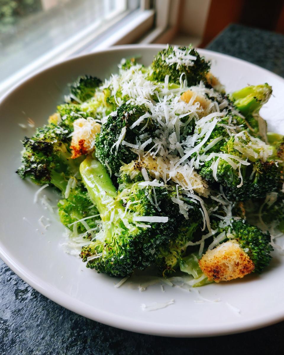 Close-up of Roasted Broccoli Caesar Salad topped with shredded Parmesan cheese and golden croutons.