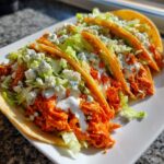 Four crispy tacos filled with bright orange shredded buffalo chicken, lettuce, blue cheese crumbles, and ranch dressing.