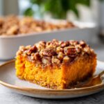 A square slice of vibrant orange Southern Maple Sweet Potato Casserole topped with pecans.