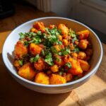 Close-up of a bowl filled with Spicy Curry Chickpea Potatoes, topped generously with fresh cilantro.