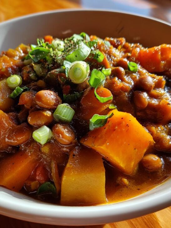 Close-up of Spicy Vegan Jamaican Stew Peas with large chunks of pumpkin and topped with fresh scallions.