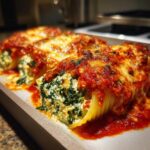 Close-up of baked Stuffed Shells Florentine, overflowing with ricotta and spinach filling, topped with marinara sauce and melted cheese.