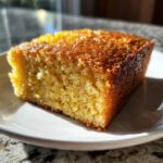 Close-up of a moist, golden slice of Two Ingredient Lemon Cakes on a white plate.