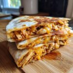 Three stacked, golden-brown wedges of chicken quesadillas oozing with melted cheddar cheese, ready for Preparing Chicken Quesadillas Using An Air Fryer.