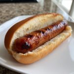 A plump, grilled hot dog nestled in a soft bun, showing char marks from Preparing Hot Dogs Using An Air Fryer.