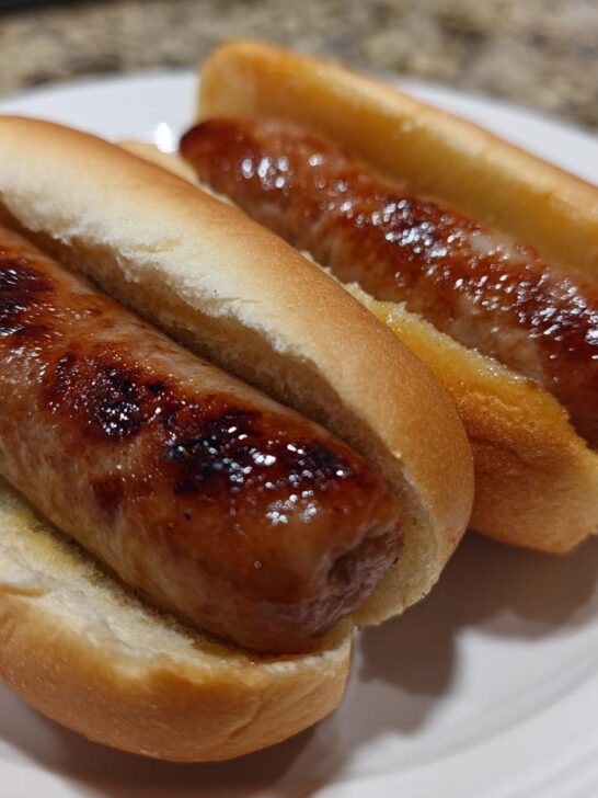 Two plump, browned hot dogs nestled in soft buns, ready to eat after preparing hot dogs using an air fryer.