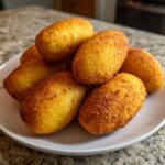 A pile of golden brown, crispy air fryer mini corn dogs with cornbread swirls stacked on a white plate.