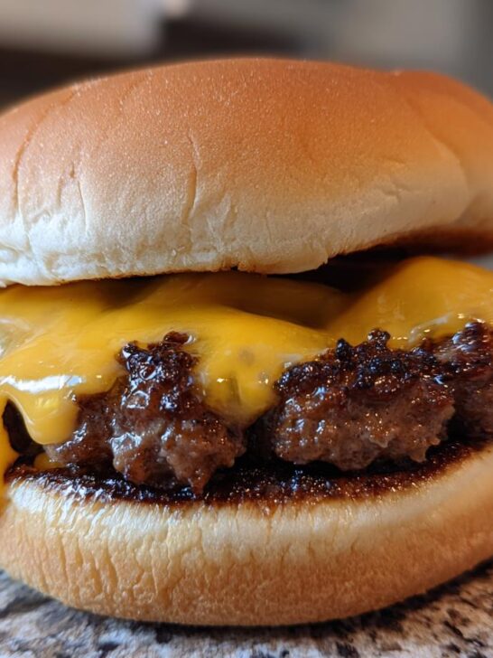 Close-up of a juicy cheeseburger with melted American cheese, cooked using the Burgers In A Ninja Foodi Air Fryer method.