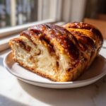A cross-section of a rich Apple Cinnamon Babka loaf showing soft interior and glossy, caramelized topping.