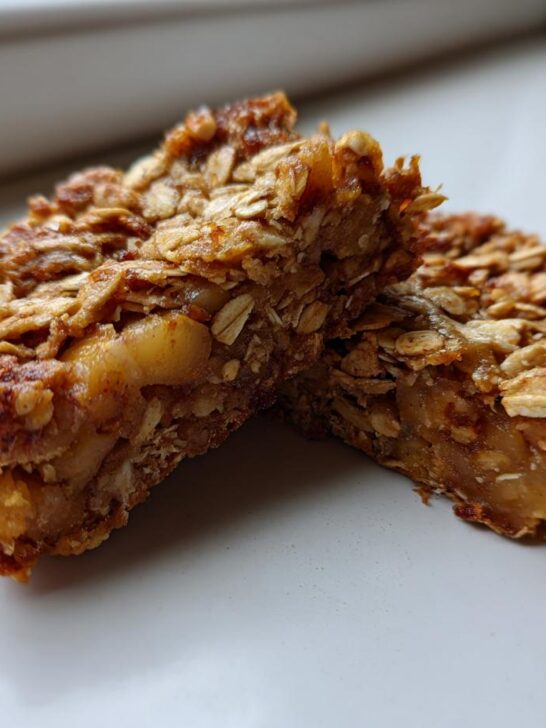 Close-up of two chewy Apple Cinnamon Breakfast Bars stacked slightly, showing oats and apple filling.