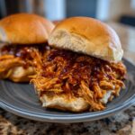 Close-up of a delicious Bbq Pulled Chicken Sliders piled high with saucy shredded chicken on soft slider buns.