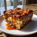 A close-up of a square slice of Caramel Apple Stuffed French Toast Casserole drizzled with caramel sauce.