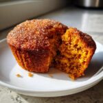Close-up of a Cinnamon Sugar Pumpkin Muffins, cut open to show the moist, orange interior texture.