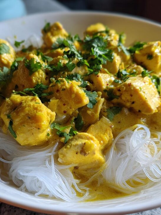 Close-up of Coconut Curry Chicken With Rice Noodles, featuring yellow curry sauce and fresh cilantro garnish.