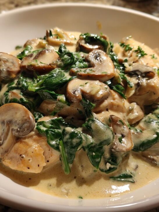 Close-up of chicken breasts smothered in a creamy sauce with mushrooms and spinach from the Creamy Chicken Mushroom Spinach Skillet.