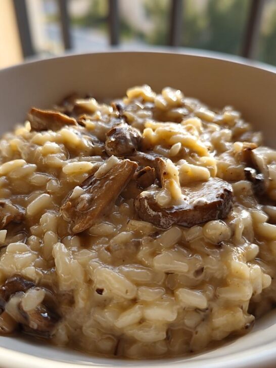 Close-up of rich, creamy mushroom risotto served in a white bowl, perfectly cooked.