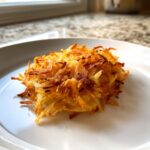 A perfectly golden and crispy serving of Air Fryer Hash Brown Potatoes on a white plate.