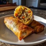 Close-up of crispy Air Fryer Pork Egg Rolls, one cut open to show savory ground pork and shredded cabbage filling.