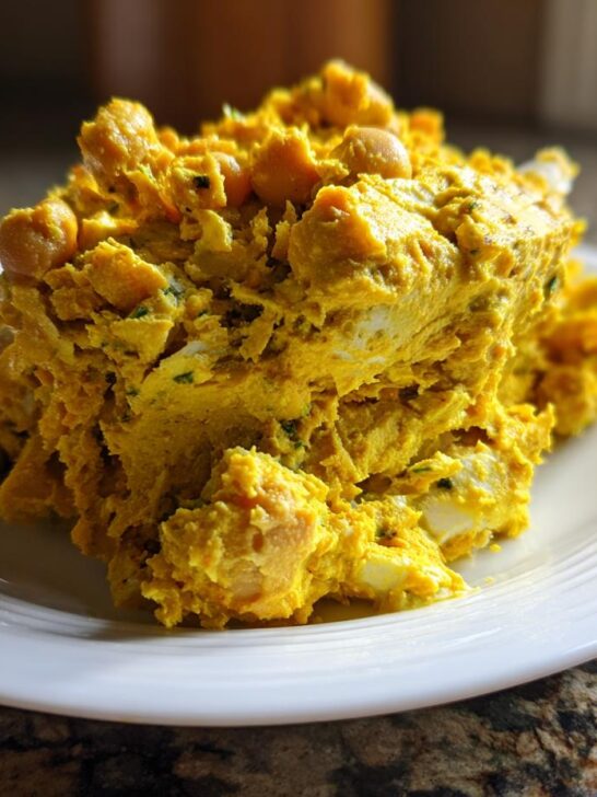 A mound of vibrant yellow Curried Chickpea Salad served on a white plate.