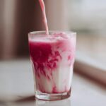 Pink strawberry syrup swirling into white milk to create Easy Quick Strawberry Milk in a clear glass.