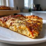 Close-up of a thick slice of Grandmas Cheese Sheet Pan Pizza with bubbly cheese and herbs.