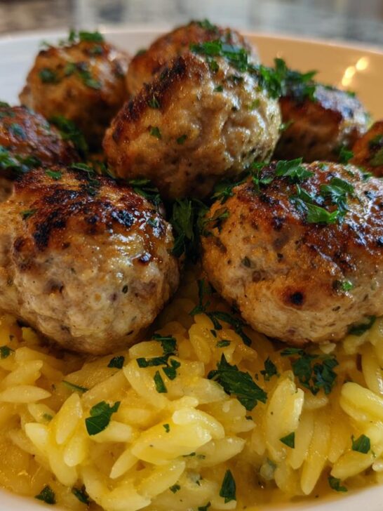 Close-up of perfectly browned Greek Chicken Meatballs served over creamy lemon orzo pasta.