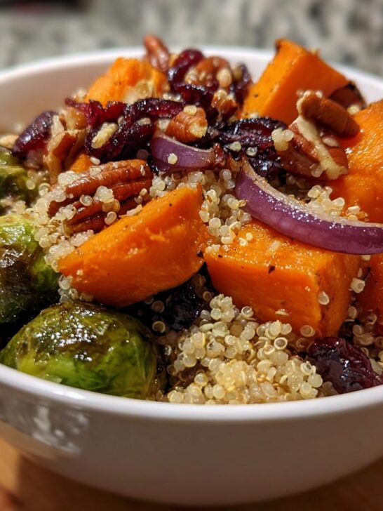 Close-up of a vibrant Harvest Quinoa Bowl featuring roasted sweet potatoes, Brussels sprouts, pecans, and dried cranberries.
