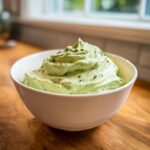 A close-up of thick, creamy Healthy Green Goddess Salad Dip, swirled high in a white bowl and garnished with fresh herbs.