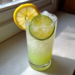 A tall glass filled with a bubbly Jalapeno Lemon Lime Mocktail, garnished with fresh lemon and lime slices.
