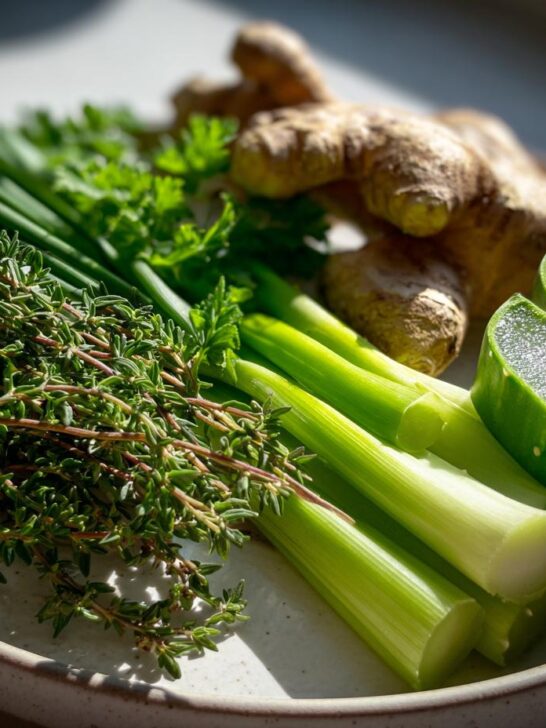 A plate featuring fresh thyme, celery stalks, ginger root, and cut aloe vera, representing Jamaican Herbs That You Should Always Keep On Hand Remedies.