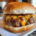 Close-up of a perfectly cooked cheeseburger patty with melted cheddar cheese, ready to eat, made using Burgers In A Ninja Foodi Air Fryer.