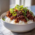 Close-up of a Korean Ground Beef Bowl featuring savory ground beef over white rice, topped with sesame seeds and fresh green onions.