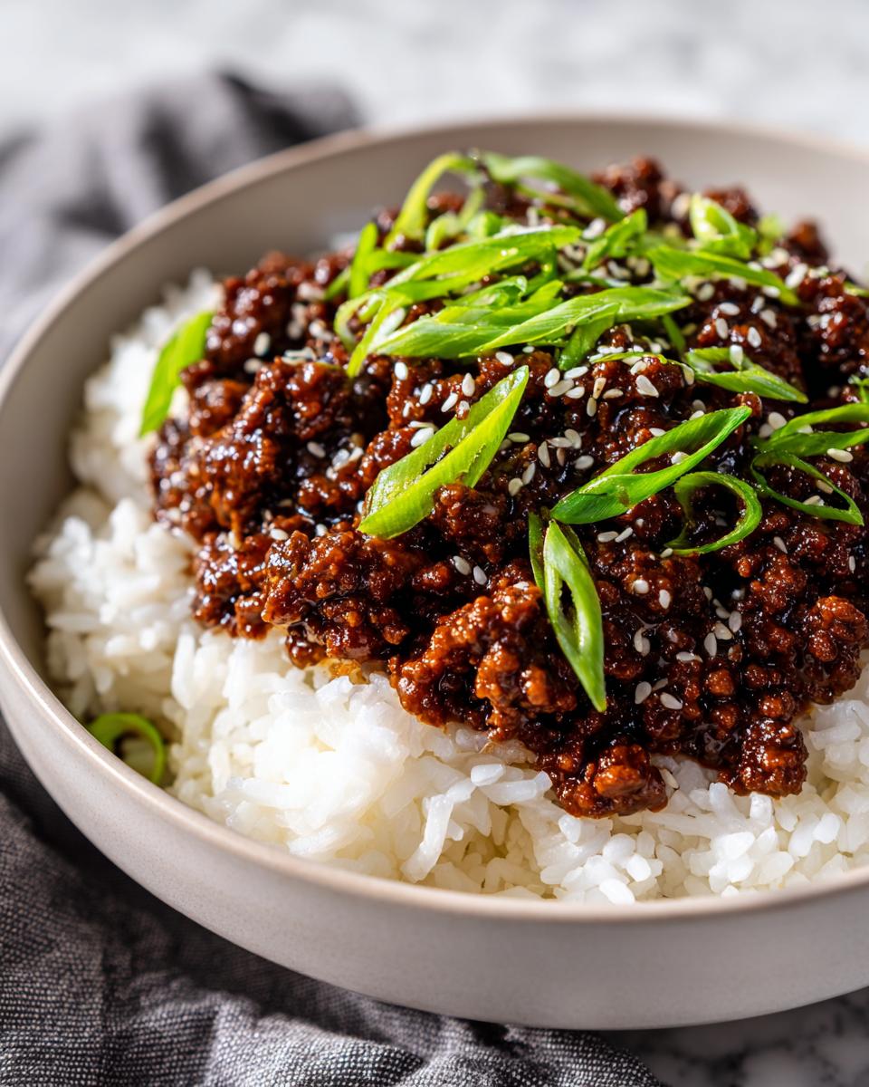Close-up of a Korean Ground Beef Bowl featuring savory ground beef over white rice, topped with green onions and sesame seeds.