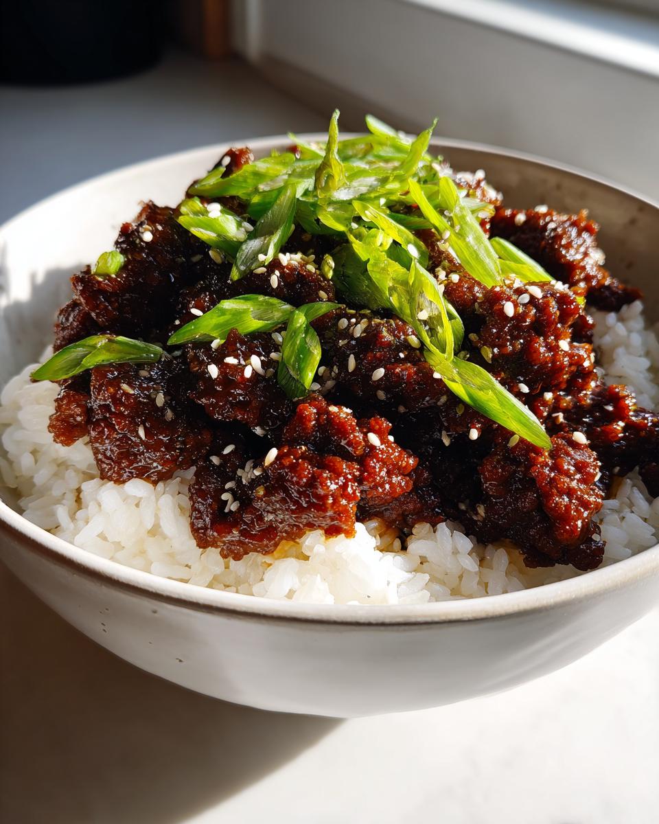 A close-up of a Korean Ground Beef Bowl featuring savory ground beef over white rice, topped with sliced green onions and sesame seeds.