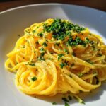 Close-up of bright yellow Lemon Butter Linguine tossed in sauce and topped with fresh chopped parsley.