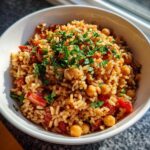 Close-up of a white bowl filled with flavorful Mediterranean Rice And Beans, topped with fresh chopped parsley.
