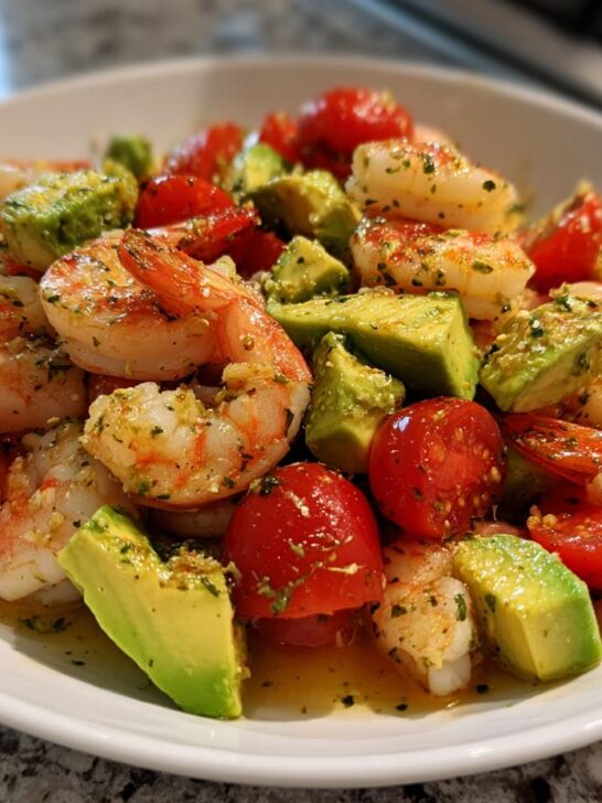 Close-up of Mediterranean Shrimp And Avocado Salad with cherry tomatoes in a white bowl.