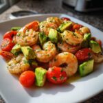 Close-up of bright, seasoned shrimp mixed with chunks of avocado and halved cherry tomatoes in a Mediterranean Shrimp And Avocado Salad.