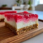 A single square of No Bake Rhubarb Cheesecake Squares showing a graham cracker crust, creamy white layer, and bright red rhubarb topping.