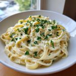 A close-up of rich, creamy fettuccine pasta topped with grated cheese and fresh parsley, representing One Pot Creamy Garlic Pasta.