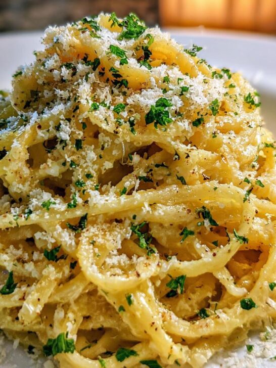 Close-up of creamy One Pot Lemon Garlic Parmesan Pasta topped generously with grated cheese and fresh parsley.