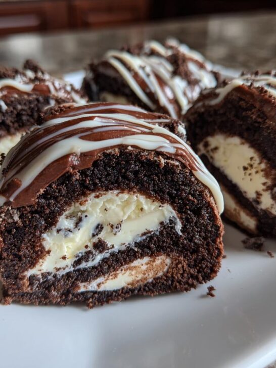 Four cross-sections of rich Oreo Sushi Rolls filled with cream, drizzled with chocolate and white icing.