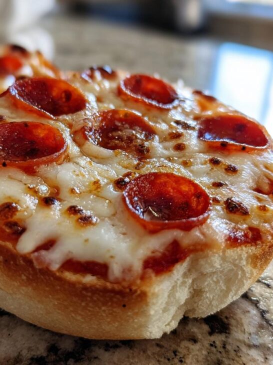 Close-up of a freshly baked English Muffin Pizza topped with melted cheese and pepperoni slices.