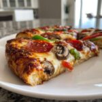 Close-up of a thick-crust pizza slice featuring pepperoni, mushrooms, and peppers, showcasing some of the Best Pizza Toppings For Any Night.