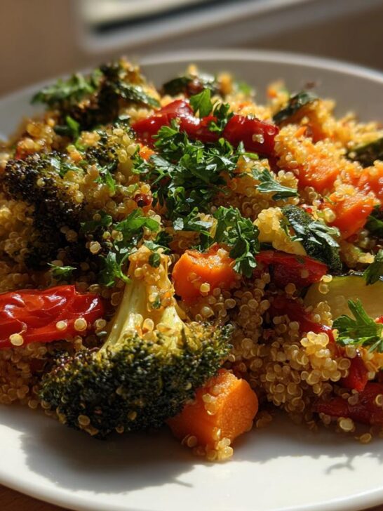 Close-up of Quinoa Salad With Roasted Vegetables featuring broccoli, carrots, zucchini, and tomatoes, garnished with parsley.