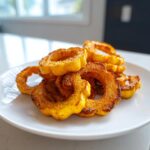 A pile of perfectly seasoned and crispy Roasted Delicata Squash rings served on a white plate.