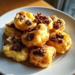 A close-up of several golden brown Sausage Pancake Bites piled on a white plate, catching the sunlight.