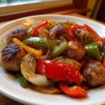 Close-up of browned sausage pieces mixed with roasted red, green, and yellow peppers and onions from Sheet Pan Sausage Peppers And Onions.