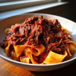 A close-up of a bowl filled with wide pappardelle pasta topped generously with rich Slow Cooker Beef Ragu.