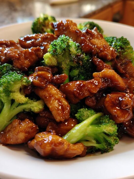 Close-up of glistening Teriyaki Chicken And Broccoli Stir Fry served on a white plate.
